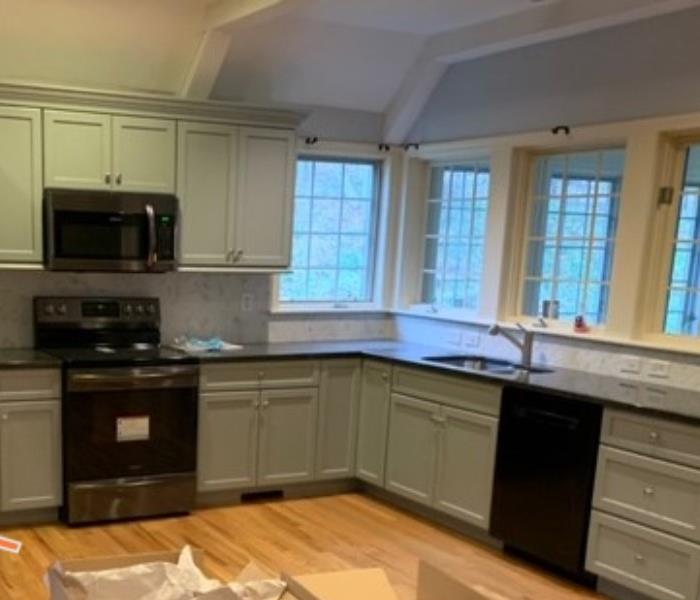 kitchen with wood floors gray cabinet, modern appliances, servpro logo