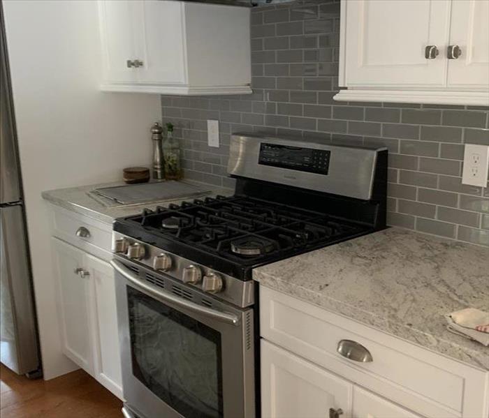 kitchen with white cabinets, granite counter, range, fire damage, hood, oak hardwood floor