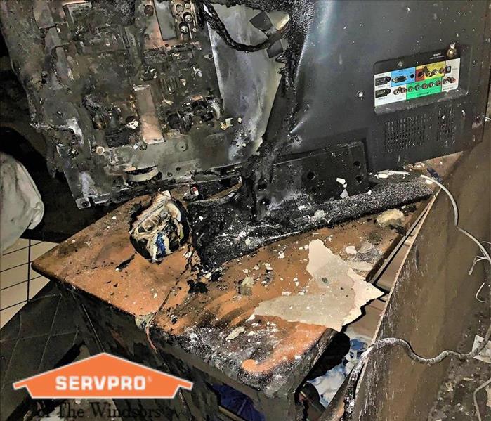  tv that has been melted by fire is sitting on top of a dresser that also has fire damage SERVPRO of The Windsors Logo