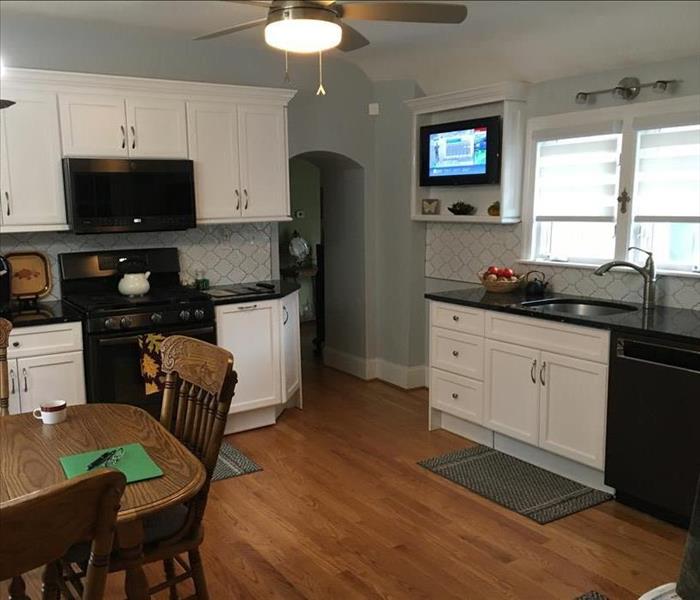 Kitchen, grey walls white back splash and cabinetry, black counter tops, appliances, wood floor, kitchen table