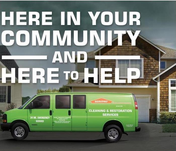 Green SERVPRO van parked on street in residential area, brown house and driveway in background,